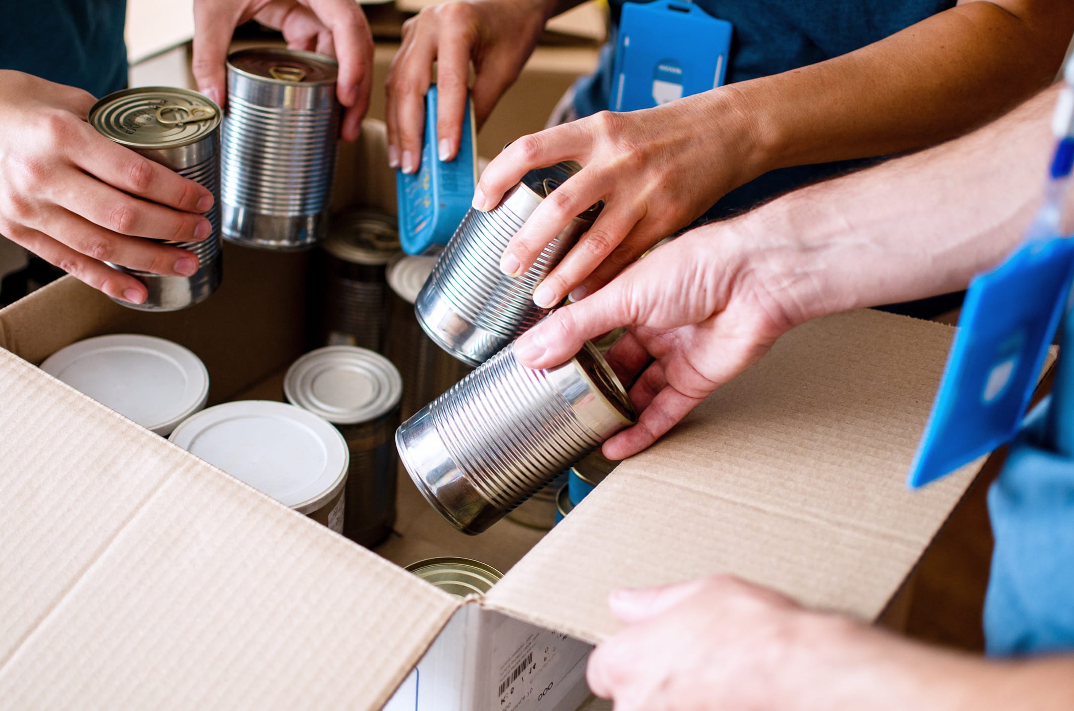 Volunteers Packing humanitarian aid in donation box. Group of unrecognizable people working in charitable foundation helping in crises and homeless.Donation and charity concept